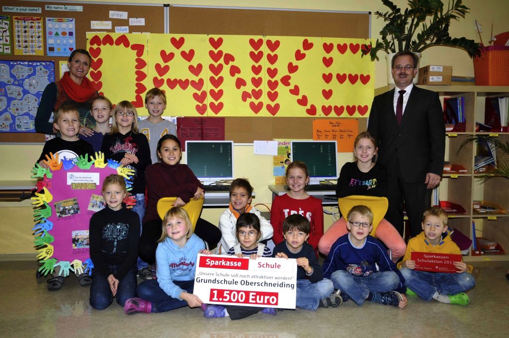 Unser Bild zeigt die Scheckübergabe mit Rektorin Sonja Urban (links) und Geschäftsstellenleiter Reiner Mittig (rechts) und einigen Kindern.